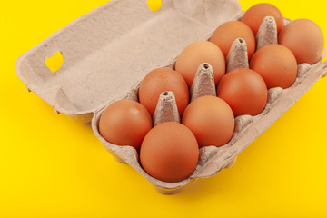 Egg Chicken eggs. Top view of an open gray box with brown eggs Isolated on a yellow background. The concept of a healthy lifestyle, getting pure protein. Proper Breakfast. .