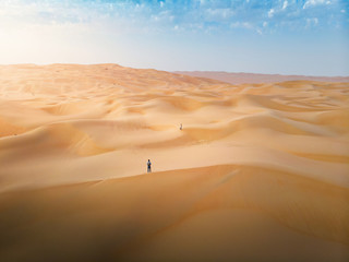 Wall Mural - Couple among desert sand dunes aerial view