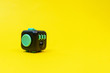 Black and green fidget cube on yellow background, minimal concept, copyspace. 