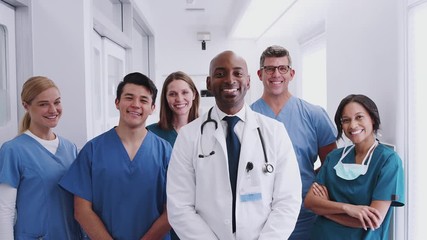 Wall Mural - Portrait Of Smiling Multi-Cultural Medical Team Standing In Hospital Corridor 