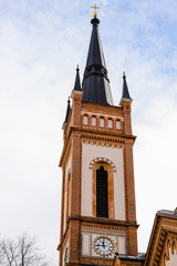 Bell tower of an old red brick church with a Vienna clock.