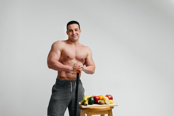 Sexy vegan guy with a naked torso posing in the Studio next to fruit. Diet. Healthy diet