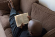 © magicbones - Black man, of African ethnicity, reading on the sofa
