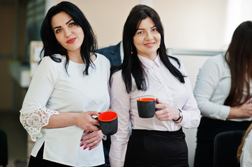 Young business people group of bank workers have meeting and working in modern office. Two female have coffe break with cup on hands.