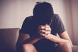 © SewcreamStudio - Depressed, and anxiety young man sitting alone and praying at home, social distance, mental health, men health, online home church concept
