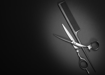 Scissors and comb. Beauty salon equipment. Shears for haircut on black background. Copy space, flat lay view