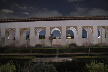 Asean young man enjoying the view in the Gardens and famous traditional Spanish Islamic buildings in AlHambra at night