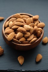 Wall Mural - Almonds nut close-up. almonds in a round wooden cup on a black slate background. Nuts in a cup.Vegetarian and vegan food.Healthy food.
