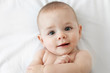 © Lisa Tichané - Overhead portrait of smiling baby lying on white bed