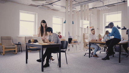 Wall Mural - Multiethnic team working in modern trendy office. Happy young smiling creative millennials work in light coworking 4K.