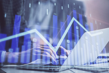 Double exposure of market chart with man working on computer on background. Concept of financial analysis.