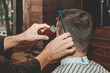 © Natalya Lys - Haircut at the hairdresser. Barber cuts the hair on the client's head. The process of creating hairstyles for men. A man in a barbershop. The near plan. Equipment stylist. Selective focus