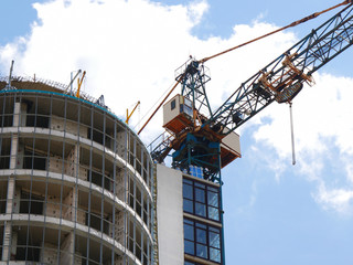 Industrial crane near building against blue sky. Construction site.