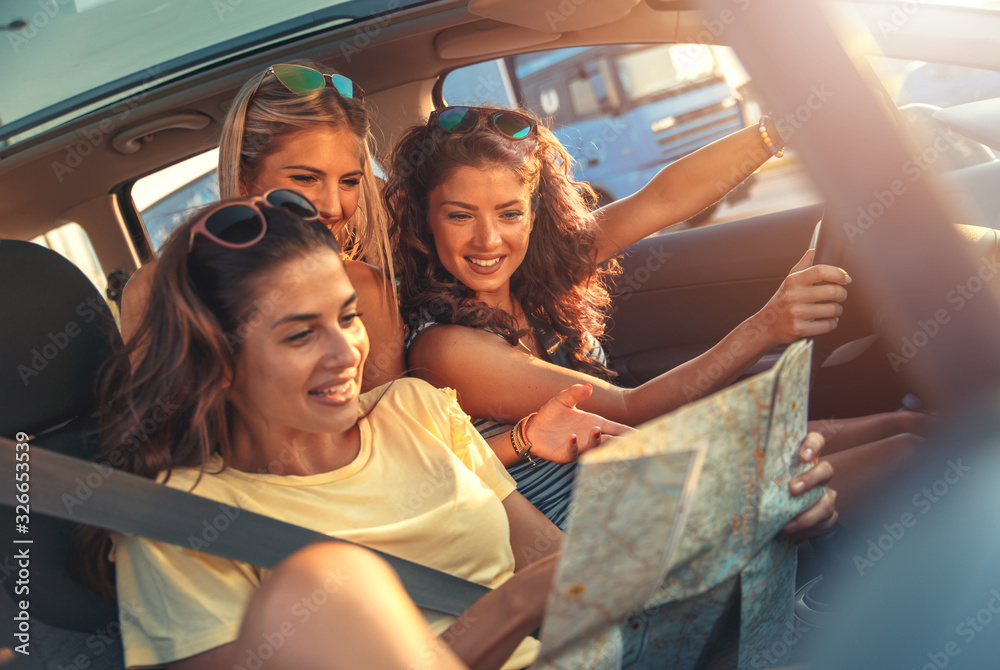 Three female friends enjoying road trip traveling at vacation in the car. - obrazy, fototapety, plakaty 