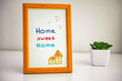 © rosinka79 - Home sweet home picture in wooden frame and small houseplant on the table.