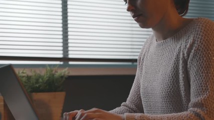 Wall Mural - Woman sitting at desk and typing with her laptop