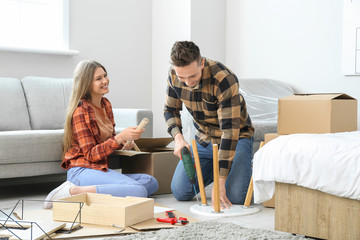 Young couple assembling furniture at home