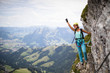 Pretty, female climber on a via ferrata -  climbing on a rock in Swiss Alps