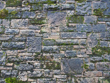 An Old Grey Stone Wall Made Of Large Irregular Blocks Covered In Patches Of Moss