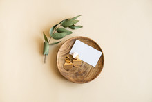 Natural Branch With Leaves And Gold Earrings In Wooden Plate On Beige Background