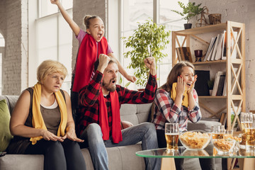 Excited, happy big family watching football, soccer, basketball, hockey, tennis, rugby match on the couch at home. Fans emotional cheering for favourite national team. Sport, TV, championship.