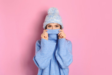 Canvas Print - Young woman wearing warm sweater and hat on pink background. Winter season