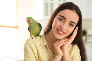 Wall Mural - Young woman with Alexandrine parakeet indoors. Cute pet