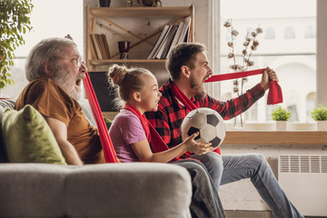 Wall Mural - Excited, happy big family watching football, soccer match on the couch at home. Fans emotional cheering for favourite national team. Having fun from grandpa to daughter. Sport, TV, championship.