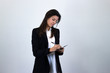 © Sergio Barceló - Portrait of attractive caucasian bussiness woman model with a folder in her hands, isolated on gray background studio shot, white shirt and black jacket, dark air. Place for your text in copy space.