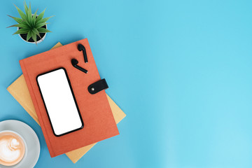 Wall Mural - Work space back to school and education concept on blue table desk with blank screen phone and stack of book, earphone, green plant and coffee cup, flat lay, Top view with copy space