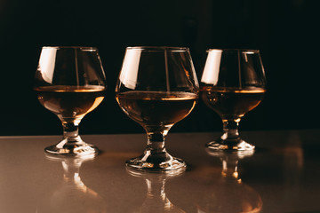 three glasses with cognac in a row on a dark background