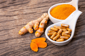 Sticker - Turmeric ( curcumin, Curcuma ) powder and tumeric capsule isolated on wood background. Supplement concept. Top view. 