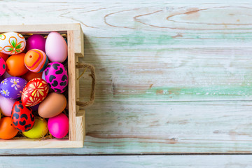 Easter holiday concept,Colorful Easter eggs in basket on white pastel color rustic wood background with space.