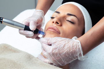 Cosmetologist making mesotherapy injection with dermapen on face for rejuvenation on the spa center.