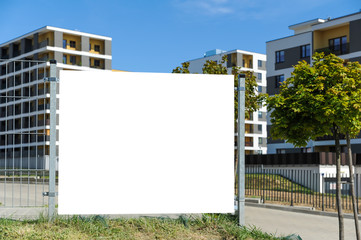 Poster - Blank white banner for advertisement on the fence. Residential area on a sunny summer day.