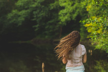 A Young Woman In White Shirt With Long Hair Fluttering In The Wind, Copy Space. Hair Flying In The Wind, In Motion .Girls Hair Fluttering In The Wind Against The Background Of The Forest. Freedom And