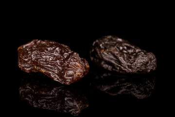 Group of two whole dried dark raisin isolated on black glass