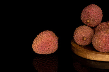 Wall Mural - Group of five whole fresh lychee on round bamboo coaster isolated on black glass