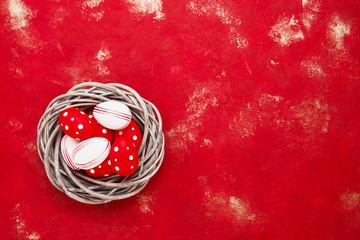 Red Easter background. Decorative Easter eggs in wreath on red background. Top view, copy space