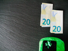 Green Hat With Shamrock Two Euro Banknotes Folded Making 2020 Year Saint Patrick Day Celebration. Dark Background, Copy Space.