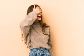 Young caucasian woman isolated en beige background covers eyes with hands, smiles broadly waiting for a surprise.