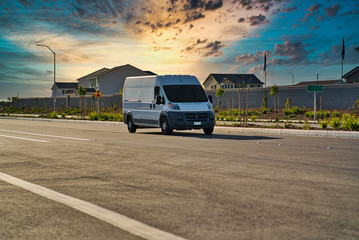 white cargo van driving down road during sunset