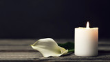 Burning candle and white calla lily on dark background with copy space. Sympathy card