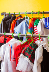 Rack with many cool holiday costumes for kids on hangers at children fashion showroom. Rental service in the cloth shop.