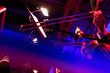 Musicians of a big band trombone section are laying down some smooth jazz during a live show in a venue with red lights and blue lights making streaks in fron of the camera