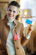 © Alliance - woman trying coat with sale price tag and holding credit card