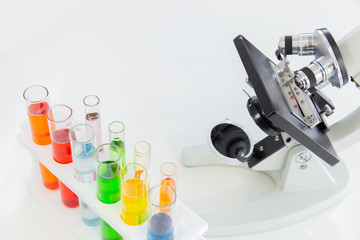 Poster - Test tubes in a stand and a microscope on a white table