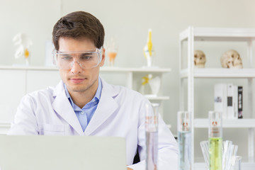 Poster - The concept of health care researchers working in biological science laboratories The young male research scientist is preparing and analyzing a slide to find information in a notebook.
