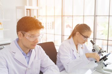Poster - concept of a healthcare researcher, a researcher working in a life science lab, a young research scientist and a male supervisor preparing and analyzing microscopic slides in a research laboratory