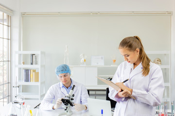 Poster - Scientists, young men and women in the laboratory and have a beautiful orange light.